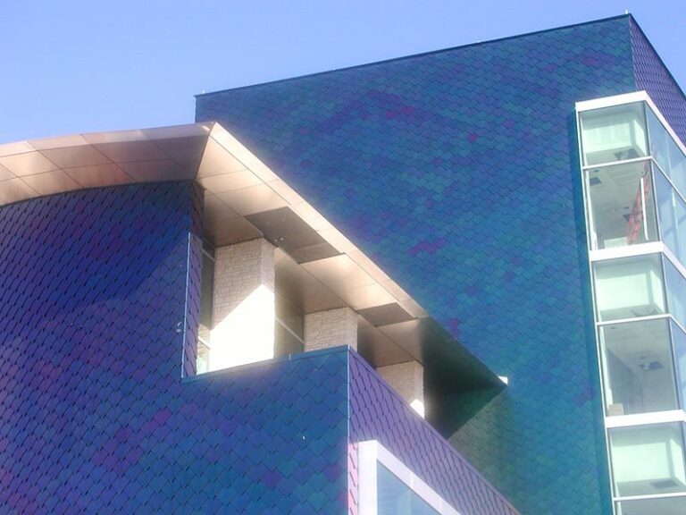 photo of blue scale textured building with blue sky backdrop