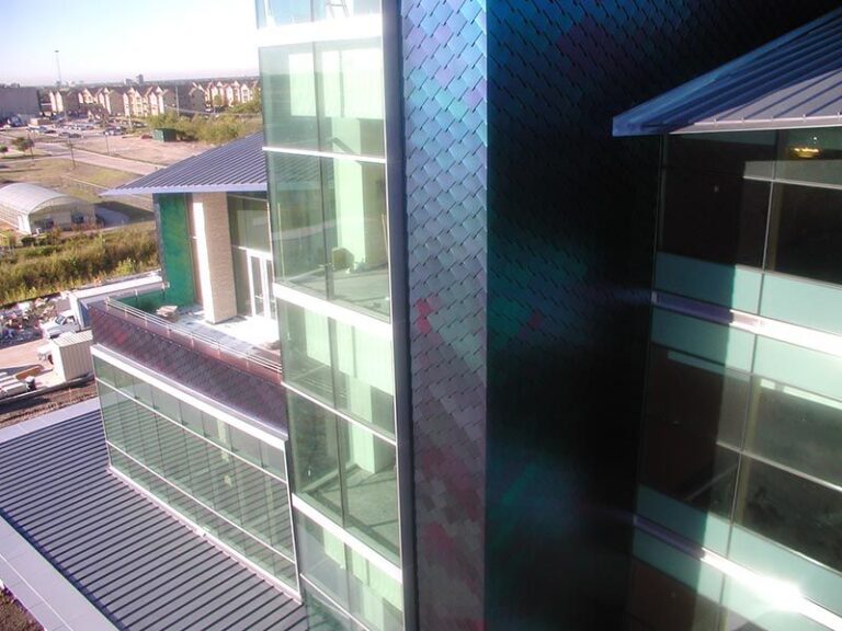 photo of blue scale textured building with blue sky backdrop