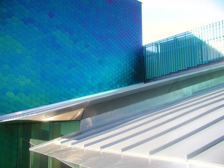 photo of blue scale textured building with blue sky backdrop